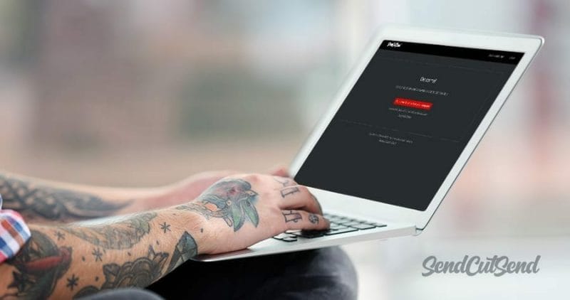 Image of someone with tattoos on a laptop getting ready to upload their file for instant quoting with a SendCutSend discount code.