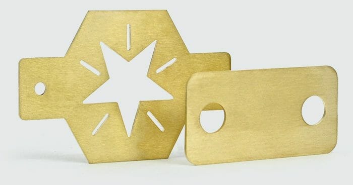 Image of two laser cut brass parts on a white background