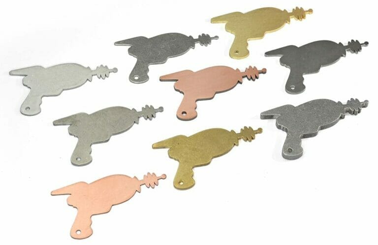 9 laser cut parts in the shape of laser guns showing different deburred materials.