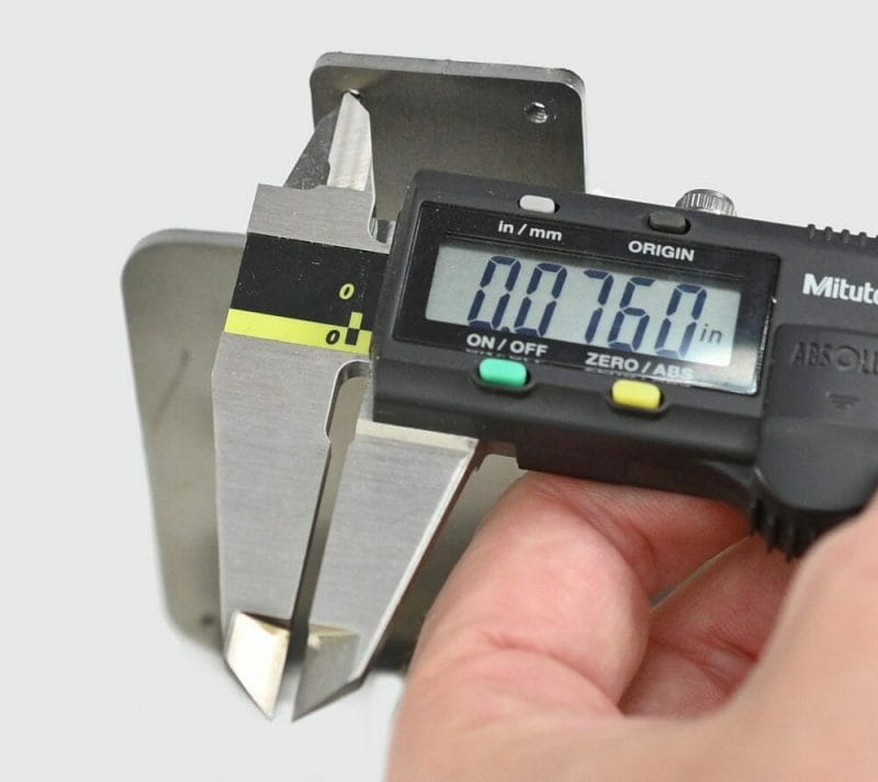Someone holding a set of inch/metric calipers that read "0.0760 in"