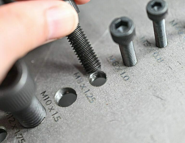 Close up image of a tap size tool with corresponding screws screwed into each tapped hole