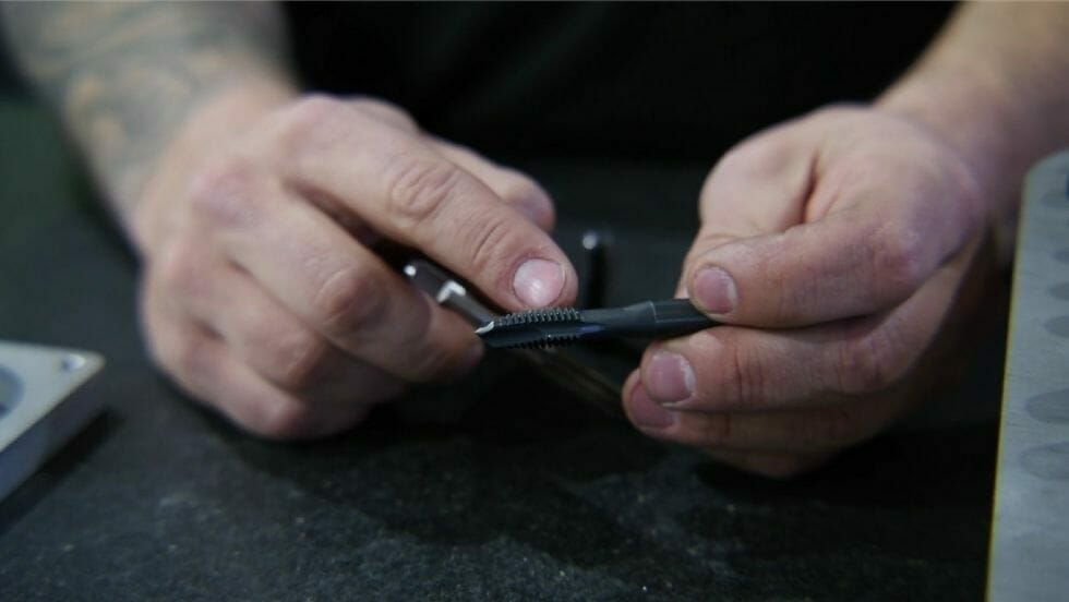 Screenshot from the video showing a close-up view of a tap, the tool used for tapping laser cut holes