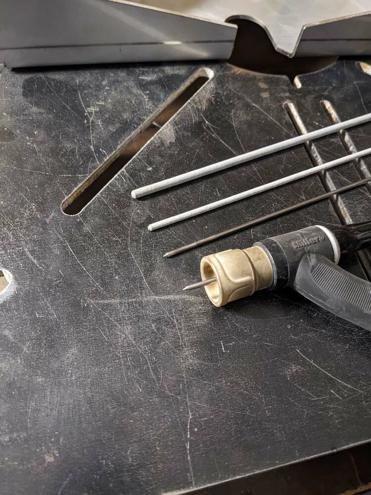 Image of two stick welding electrodes coated with flux, and a TIG noncoated electrode with torch.