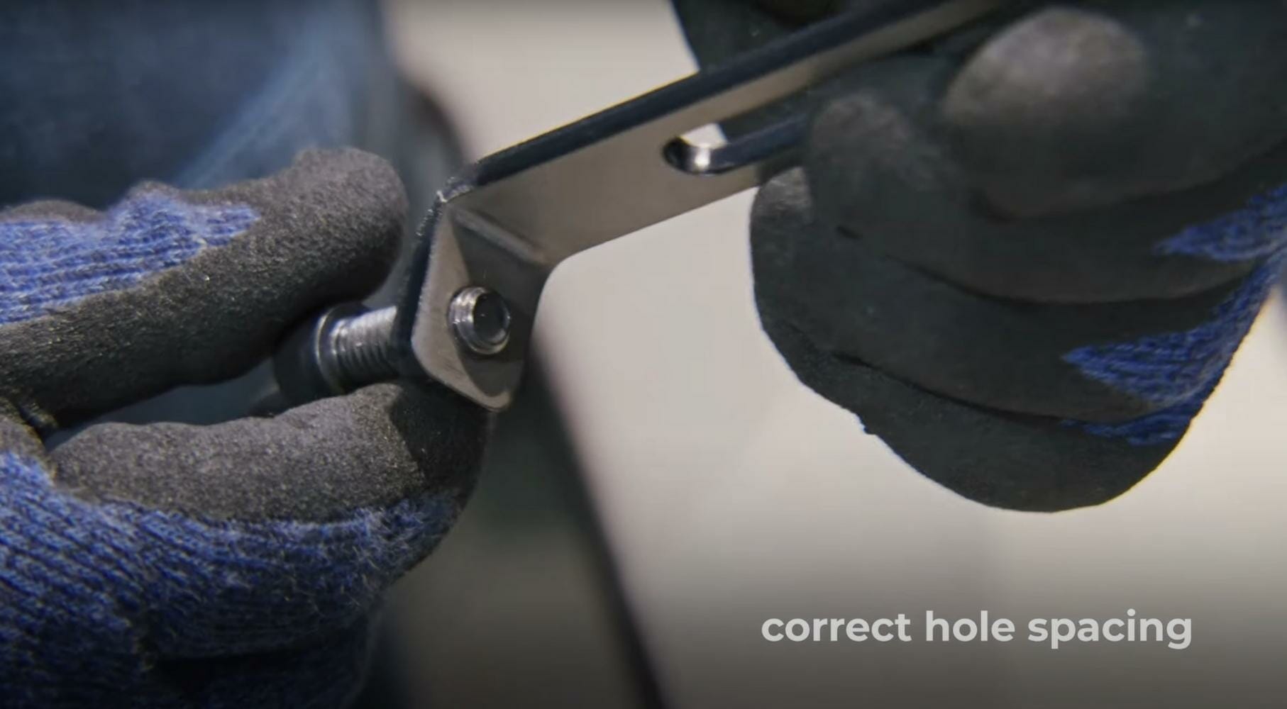 Screenshot from the video of a similar bent part with the hole spaced far enough away from the die line as to not compromise the feature. This is denoted with "correct hole spacing" written in the bottom right corner