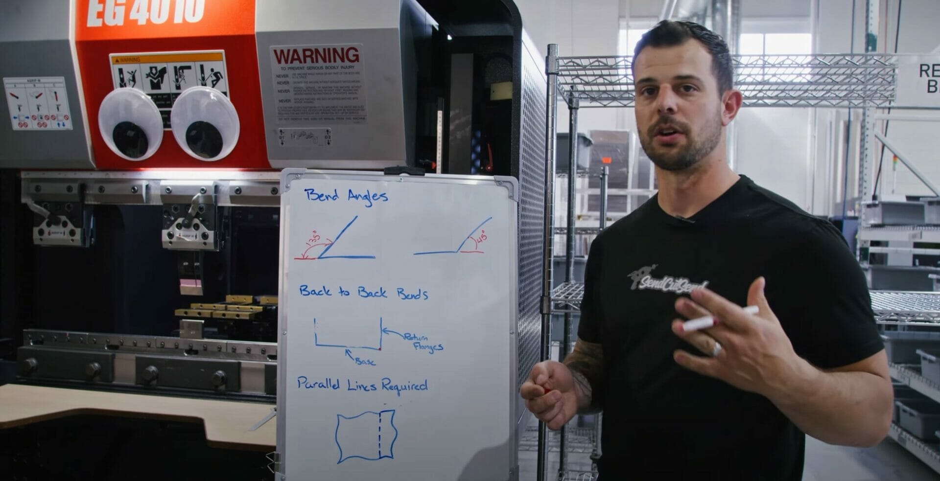 Screenshot of the video "Design Considerations When Planning Sheet Metal Bends" that shows Jake illustration obtuse and acute angles on a whiteboard in front of a CNC brake.