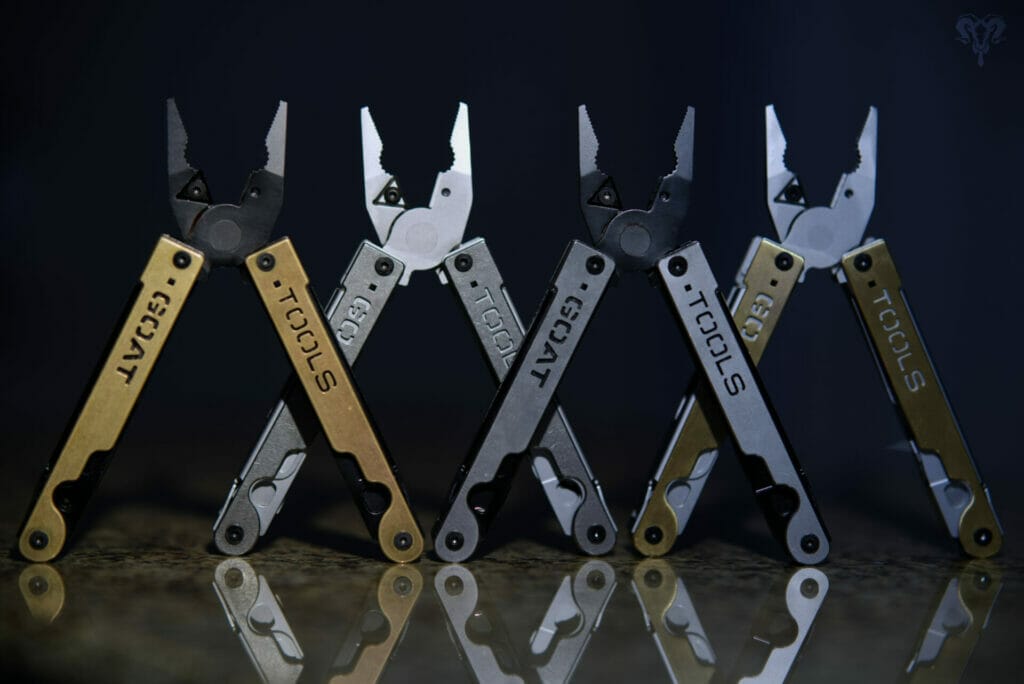 Image of 4 customizable multitools from GOAT Tools, opened and standing upright against a dark background